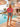 T-shirt rosa feminina com estampado La Dolce Vita Beach Club, palmeiras, espreguiçadeiras e inspiração tropical de verão.
